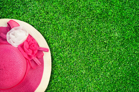 Pink summer hat with silk roses flowers at green texture of garden grass. Image in vintage styleの写真素材