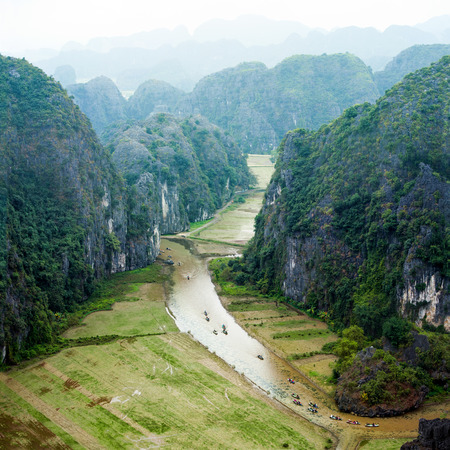 Tourist boats floating on the river among rice fields and limestone rocks in the early morning at...