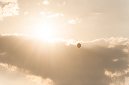 Amazing colors of sunrise with sunbeams over clouds and hot air balloon silhouetteの写真素材