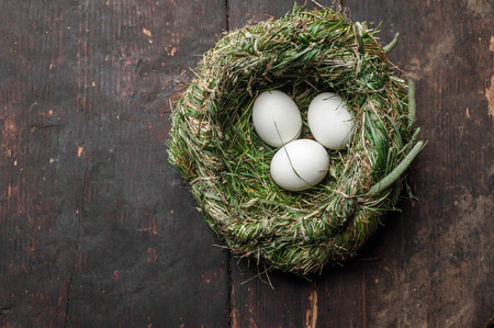 Organic white eggs in hay nest at wooden table