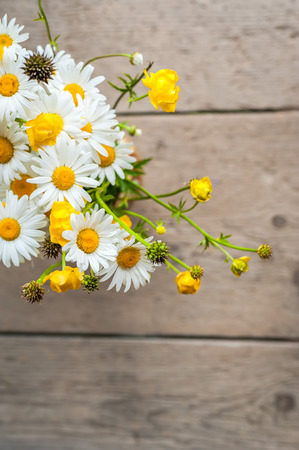 Beautiful tender bouquet of summer meadow flowers with wild chamomiles on wooden background. Floral composition in rural vintage styleの写真素材