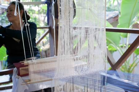 LUANG PRABANG, LAOS - 8 DEC, 2013: Unidentified woman weaving silk in traditional way at manual loom. Laosのeditorial素材