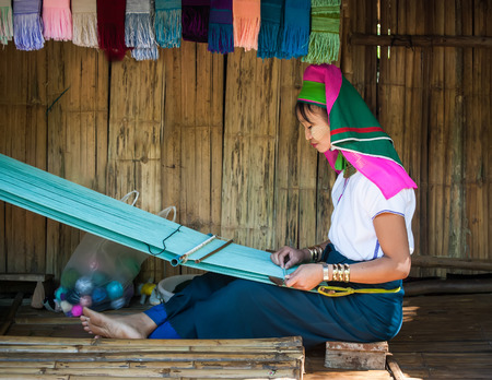 MAE HONG SON, THAILAND - DEC 4, 2013: Unidentified Karen (Kayan Lahwi Padaung) Long Neck woman with traditional brass coils working at hand loom in tribe village. Chang Mai province, Thailandのeditorial素材
