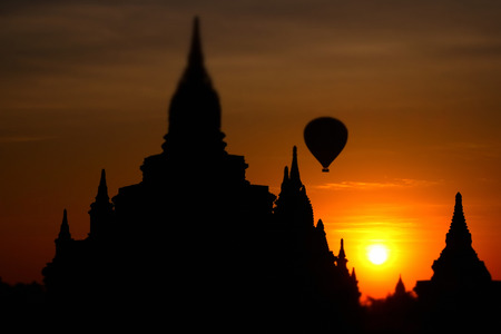 Ancient Buddhist Pagoda silhouette and balloon flying at amazing sunrise. Architecture of old Temples at Bagan Kingdom, Myanmar (Burma) travel landscapes and destinations. Tilt shift effectの写真素材