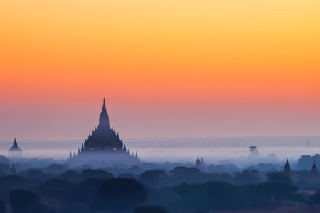 Tilt Shift blur effect. Amazing misty sunrise colors and silhouette of ancient Myauk Guni Pagoda. Architecture of ancient Buddhist Temples at Bagan Kingdom. Myanmar (Burma) travel destinationsの写真素材