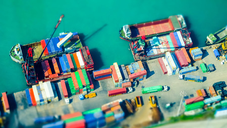 Tilt shift blur effect. Aerial view cargo ships loaded by crane with cargo containers at a busy port terminal. Hong Kongの写真素材