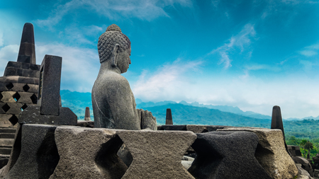 Amazing statue of Buddha sitting in stupa and looking towards gorgeous natural landscape at Candi Borobudur, temple in Magelang, Central Java, Indonesia. Meditation conceptの写真素材