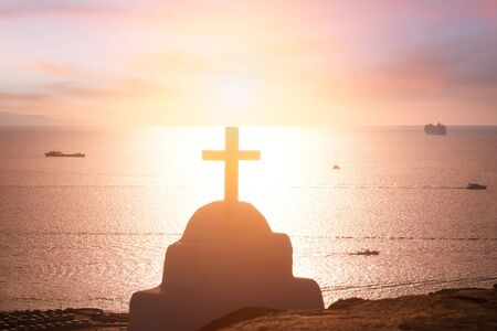 Amazing sunset colors of Aegean sea. Orthodox church cross, christianity religion symbol. Mykonos island. Greeceの写真素材