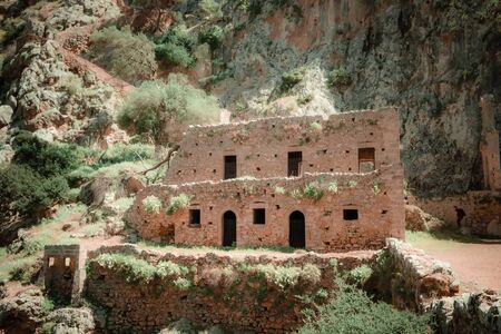 View of ruins of abandoned Katholiko monastery church on sunny Crete island. Beautiful mediterranean nature of Greece. Unique stone construction in the rock. Iconic ancient landmarkの写真素材
