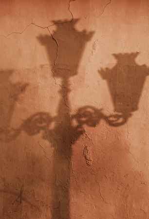 Shadow of old street lamp post on wallの写真素材