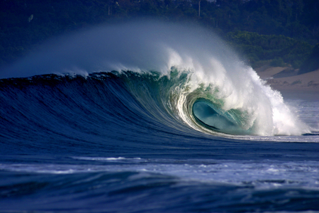 Tubular surfing wave breaking onto tropical beachの写真素材