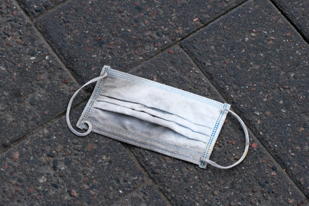 Used face mask on the groundの写真素材