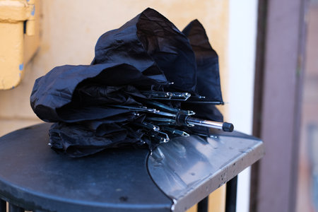 A broken black umbrella on a trash binの写真素材