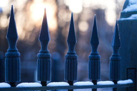 Spikes of an iron fence with snow