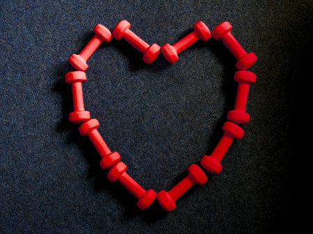 Frame in shape of heart made from red dumbbells on black background. Healthy fitness lifestyle flat lay composition for Valentine's Day, birthday, International womens day, anniversary or weddingの写真素材
