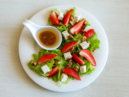 Plate of homemade fresh summer sliced Strawberry and lettuce salad with feta cheese and walnuts. Organic healthy diet, vegetarian salad food. Top viewの写真素材