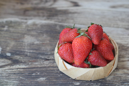 Fresh strawberries in a bamboo bowl on an old wooden background, horizontal, copy spaceの写真素材