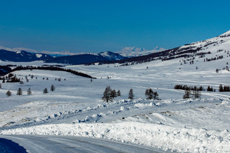 View to Jazator river valley in winter day. Russia South Of Western Siberia, Altai Mountains. Desert mountains and country road covered with snow near village of Jazator. Sailungemskiy national parkの写真素材