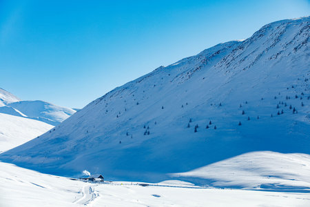 One small house in snow under mountain of South Chui ridge in winter day. Russia South Of Western Siberia, Altai Mountains. Desert mountains covered with snow near village of Djazatorの写真素材