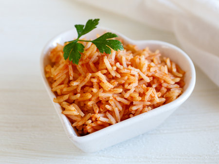 Tomato onion rice, Tamatar Biryani, jollof in white heart shape bowl on a white wooden table, horizontal. Love valentine day dinner conceptの写真素材