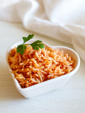 Tomato onion rice, Tamatar Biryani, jollof in white heart shape bowl on a white wooden table, vertical. Love valentine day dinner conceptの写真素材