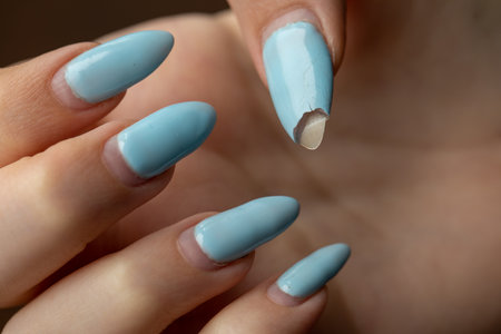Damaged nail polish of blue color on the regrowth nails of the hand with white skin. Need in correction. macro close-up. selective focus. Horizontalの写真素材