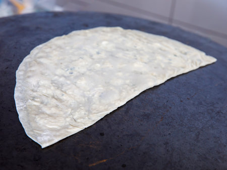 Process of making a traditional Turkish dough is called Gozleme, selective focus. It is made of flat bread stuffed with meat or cheese and baked on sheet iron or pan. Baked in a pan called a saj.の写真素材