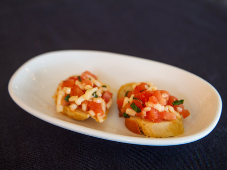 Bruschetta with fresh mozarella cheese and tomatoes on white plate. close-up view. Traditional Italian antipasti or appetizer, healthy savory toast with cheese and tomatoの写真素材
