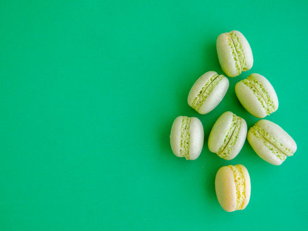 French mint pistachio green tea macarons shaped as Christmas tree on green background. Top view flat lay, copy spaceの写真素材