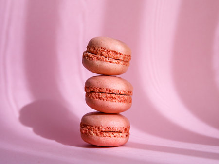 tower of pink pastel macaroons close-up on purple background with shadows, Stack of three pink strawberry raspberry cookies.の写真素材