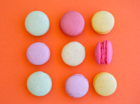 Delicious colorful Macarons almond cookies diffrent colors and flavor in square shape on bright orange background. Top view flat lay food photography. Mockup, free copy space for textの写真素材