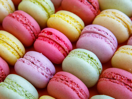 Close-up of macarons cakes of different colors on bright orange background. Culinary and cooking concept. Tasty colorful macaroons. Full frame, top view, flat lay, copy spaceの写真素材
