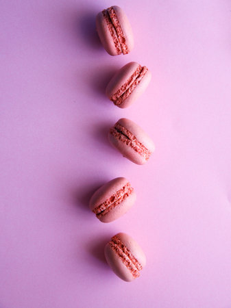 flying pink pastel macaroons close-up on light purple background. Blueberry, black currant, lavender strawberry raspberry cookies. vertical, copy space, top view, flat layの写真素材