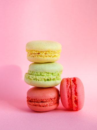 tower of multi-colored assorted bright macarons close-up on light pink background, Stack of four lemon yellow, mint green and pink cookies. Copy space, side view, verticalの写真素材