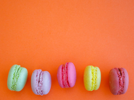Delicious colorful Macarons almond cookies diffrent colors and flavor on bright orange background. Top view flat lay food photography. Mockup, free copy space for text, border, vertical or horizontalの写真素材