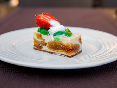 Delicious fig mousse cake slice with white chocolate cream and strawberry on top on wooden table background. Restaurant menu and confectionery concept. close-up. copyspace.の写真素材