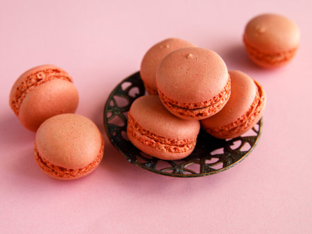 three pink pastel macaroons close-up on vintage metal plat on light pink background. Delicious strawberry raspberry cookies. Top view flat layの写真素材