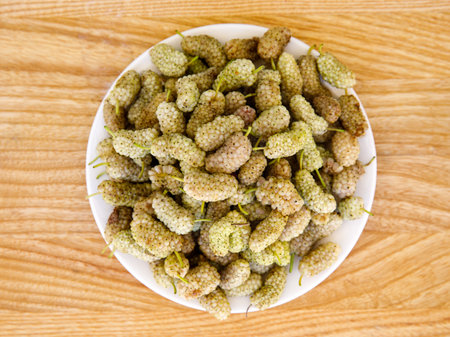 Fresh white mulberry on plate on wooden background. (Morus alba) Top view close-up. Summer organic fruits. Mulberry backgroundの写真素材