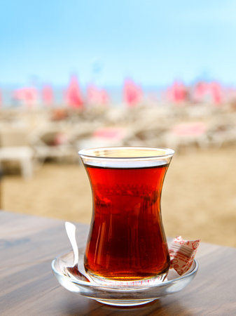 Turkish tea in a traditional glass (tulip) Bardak against the background of beach. Holiday in Turkey, travel resort. Verticalの写真素材