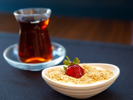 Traditional delicious Turkish milk nut Dessert Keskul - Pudding with tea in tulip glass on table. close up, top viewの写真素材