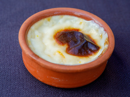 Baked rice pudding turkish milky dessert sutlac in earthenware casserole on black background, close upの写真素材