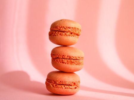 tower of pink pastel macaroons close-up on pastel pink background with shadows, Stack of three pink strawberry raspberry cookies.の写真素材