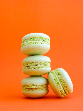 tower of mint green pastel macarons close-up on bright orange background, Stack of four pistachio or green tea cookies. Verticalの写真素材