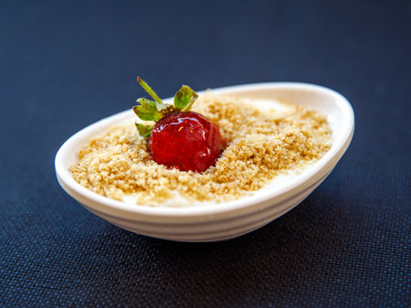 Ashure or Noah's pudding with nuts and strawberry, Turkish dessert porridge in white bowl on black table close upの写真素材