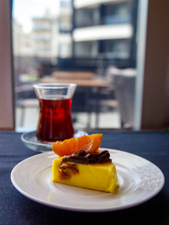 Delicious banana mango orange mousse cake slice with chocolate cream and caramelized orange on top on black table background. Restaurant menu and confectionery concept. close-up. copyspace. Verticalの写真素材