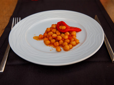 Turkish stew Cooked chickpeas in tomato sauce with red paprika on white plate over black background. Vegetarian vegan food concept.の写真素材