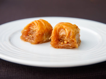 Square piece of Turkish national delight baklava with walnuts and honey on a white plate. Traditional Eastern dessert. Oriental sweet pastry. close up.の写真素材