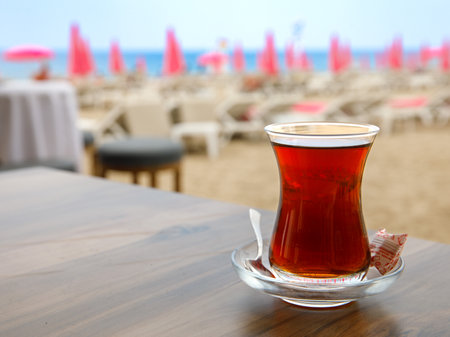 Turkish tea in a traditional glass (tulip) Bardak against the background of beach. Holiday in Turkey, travel resortの写真素材