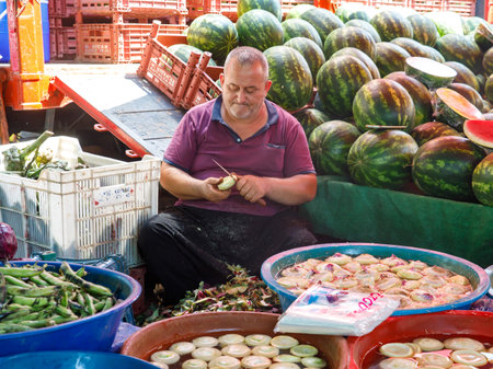Man peeling fresh artichokes on farmer market. They are in blue basins at the local market in the Mediterranean. It is sold in water with lemon so that the artichokes do not turn black. Turkeyのeditorial素材