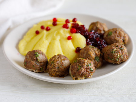Swedish Kottbullar meatball with mashed boiled potatoes and cowberry sauce on white plate on white background. close up.の写真素材